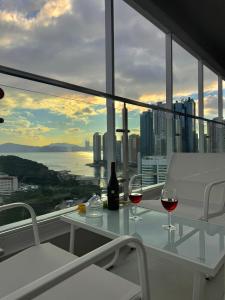 two glasses of wine sitting on a table on a balcony at Raviens Maison de Hotel in Busan