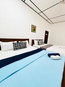 duas camas em um quarto com azul e branco em Gloriya Mathews family villa em Negombo