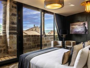 a bedroom with a bed and a large window at Mercure Figeac Viguier du Roy in Figeac