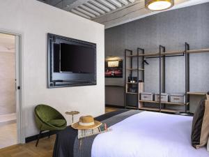 a bedroom with a bed and a flat screen tv at Mercure Figeac Viguier du Roy in Figeac +89 photos