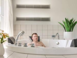a man in a bath tub in a bathroom at Luxury Pool Villa in Bagenkop - By Traum Ferienwohnungen in Bagenkop
