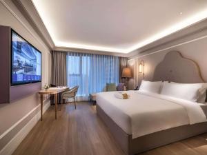 a hotel room with a large bed and a flat screen tv at Mercure Wuhan Yangluo in Wuhan +53 photos