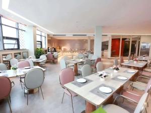 a restaurant with tables and chairs in a room at Mercure Wuhan Yangluo in Wuhan