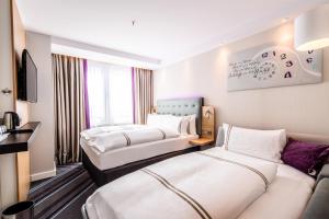 a hotel room with two beds and a couch at Premier Inn Köln City Süd in Cologne
