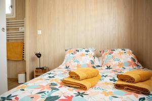 a bed with yellow pillows on it with a flower pattern at La Cabane de Camille in Pithon