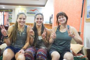 Tres mujeres sentadas en un sofá haciendo el signo de la paz en Khangsar Home, en Katmandú