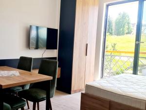 a bedroom with a table and a bed and a window at RELAX RESIDENS-kopaonik in Kopaonik