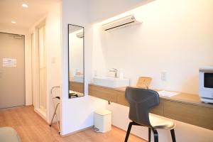a bathroom with a mirror and a desk with a chair at Yolo Hotel in Tokyo