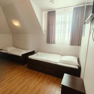two beds in a small room with a window at Gościniec Tenczyn in Tenczyn