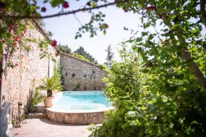 a swimming pool in a garden with a stone wall at La Roseraie in Lodève