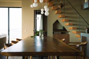a dining room with a wooden table and chairs at TORIKKA Stay -海だけが見える宿- in Sumoto