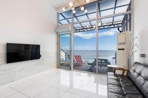 a living room with a couch and a tv and the ocean at Yeongdeok Searest Pool Villa in Changsa-ri