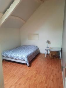 een slaapkamer met een bed en een bureau op een houten vloer bij Spacieuse maison avec piscine in Plédran