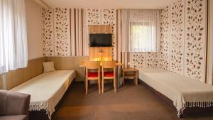 a room with two beds and a table and a tv at Hotel Fausel in Göppingen