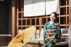 a woman in a kimono sitting next to a fan at Oukai Villa Izumi in Izumi +127 photos