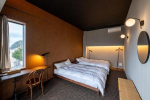 a bedroom with a bed and a desk and a window at TORIKKA Stay -海だけが見える宿- in Sumoto