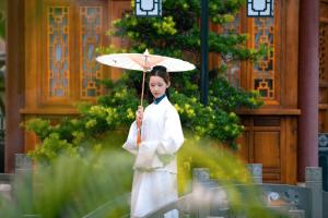 景洪市Naran manor的站在建筑物前拿着伞的妇女