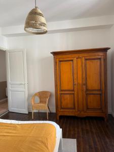 ヴェルネ・レ・バンにあるAppartement de charme et lumineux, 2 chambresのベッドルーム(木製キャビネット、椅子付) +2枚の写真