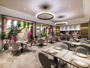 a dining room with tables and chairs and flowers at Mercure Nanjing Downtown in Nanjing