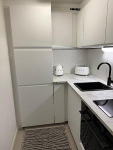a white kitchen with white cabinets and a sink at Beautiful home in the center of Rovaniemi in Rovaniemi +3 photos
