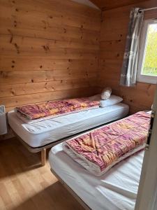 two beds in a room with a wooden wall at chalet montana 5_4 pers in Roquefeuil