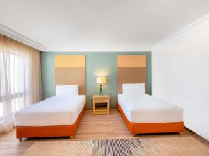 ワディ・ムーサにあるモーベンピック リゾート ペトラのベッドが2つとランプ付きのテーブルがある部屋 +186枚の写真