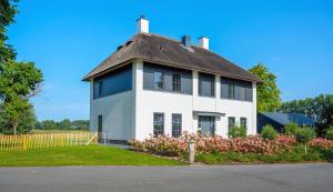 a large white house with a thatched roof at Polderhuys Goede Hope in Hoofdplaat