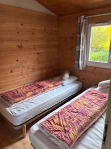 two beds in a log cabin with a window at Chalet Montana 4 pers in Roquefeuil
