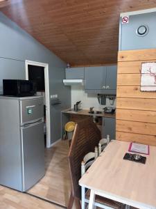 a kitchen and dining room with a table and a refrigerator at Chalet Montana pmr 4 pers in Roquefeuil