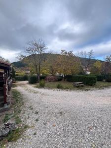 a gravel road with a bench and trees in the background at Chalet Montana pmr 4 pers in Roquefeuil +2 photos