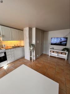 a kitchen with white cabinets and a tv on the wall at Bright and centrally studio with Oceanview in Kristiansand