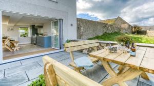 an outdoor patio with a wooden table and a kitchen at Trecastell in Rhosneigr