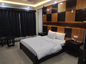 a bedroom with a large bed with a wooden headboard at Osma Living Apartment Peshawar in Peshawar