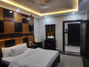 a bedroom with a large bed and a television at Osma Living Apartment Peshawar in Peshawar