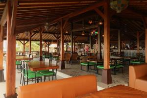 Un restaurante con mesas de madera y sillas verdes. en Mina Tanjung Hotel, en Tanjung