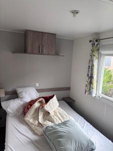 a bedroom with a white bed with pillows at Mobil-home 6 personnes in Roquefeuil