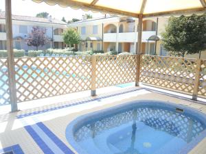 a swimming pool with a fence and a building at Villaggio Tulipano in Bibione
