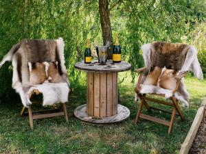 two dogs sitting in chairs around a table with bottles of wine at Poppie's Shepherds Hut at Shepherds Lodge Retreat and Wellness in Nottingham