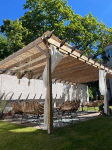 a wooden pergola with chairs and tables in a yard at Home Hotel Bilan in Karlstad