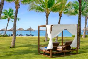 a hammock on the beach with palm trees at Royal Beachfront Villas Danang in Dien Ban