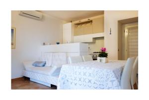 a room with a white table and chairs and a white couch at Paradiso Pool Apartments by DomusAway in Costa Paradiso