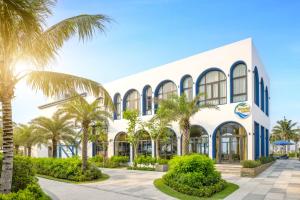 a building with palm trees in front of it at Royal Beachfront Villas Danang in Dien Ban +117 photos