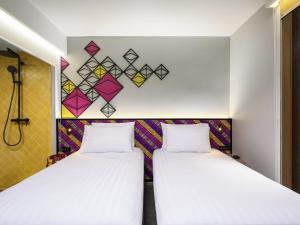 two beds in a room with a wall at ibis Styles Bangkok Silom in Bangkok