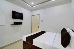 a white bedroom with a bed and a tv at Hotel O Top 22 in Ballygunge