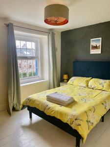 a bedroom with a bed with a yellow comforter and a window at Charming 3 bedrooms Cottage in Tirril in Tirril