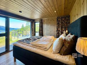 een bed in een kamer met een groot raam bij Modern cabin with panoramic view, sauna and fire pit in Espedalen