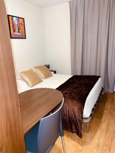 a hotel room with a bed and a wooden table at Central Fac in Bourg-en-Bresse