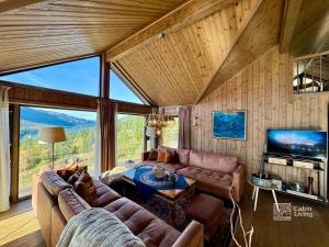 een woonkamer met een bank en een tafel bij Modern cabin with panoramic view, sauna and fire pit in Espedalen