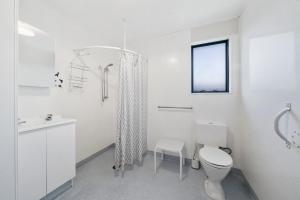 a white bathroom with a toilet and a sink at Restful on Rutherford - Waikanae Holiday Home in Waikanae +8 photos