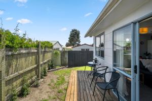 a patio with chairs and a table on a deck at Restful on Rutherford - Waikanae Holiday Home in Waikanae